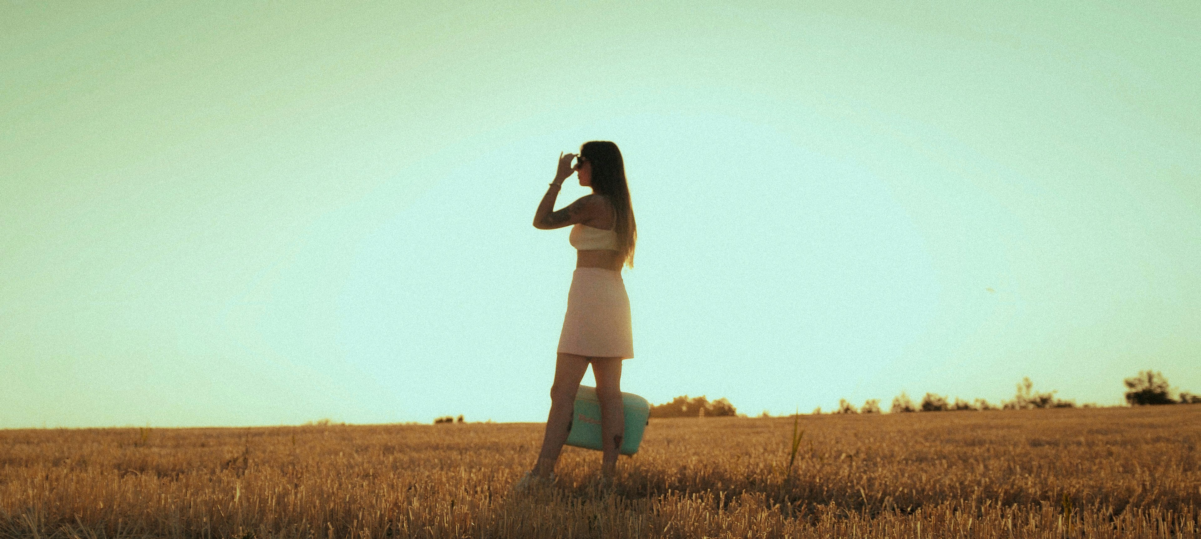 woman in white dress standing on brown grass field during daytime